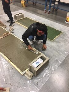 A student finishes a concrete slab, with help from a Cement Masons Local 132 apprentice, at the Columbus/Central Ohio Building Trades Job Fair