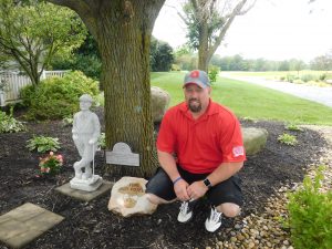 Daniel Poteet, Insulators Local Business Manager, kneels by the memorial for his father Donnie, prior to the Breadth of Life Golf Outing.